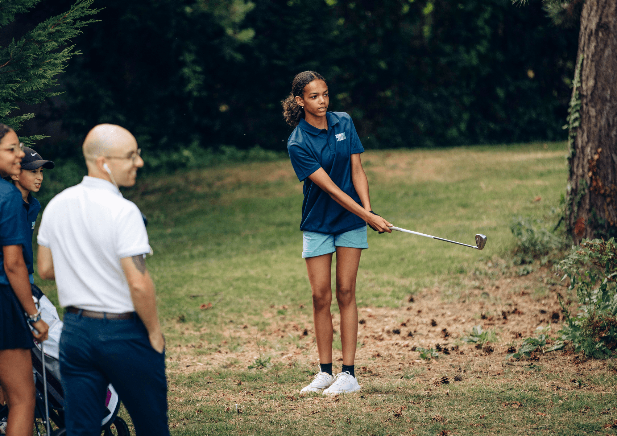 Initiation au golf : coach apprenant le putt à une enfant sur green, rentrée sportive