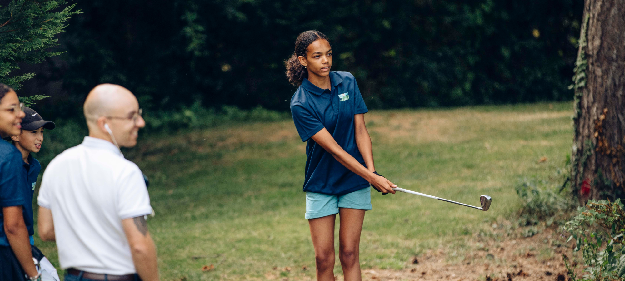 Initiation au golf : coach apprenant le putt à une enfant sur green, rentrée sportive
