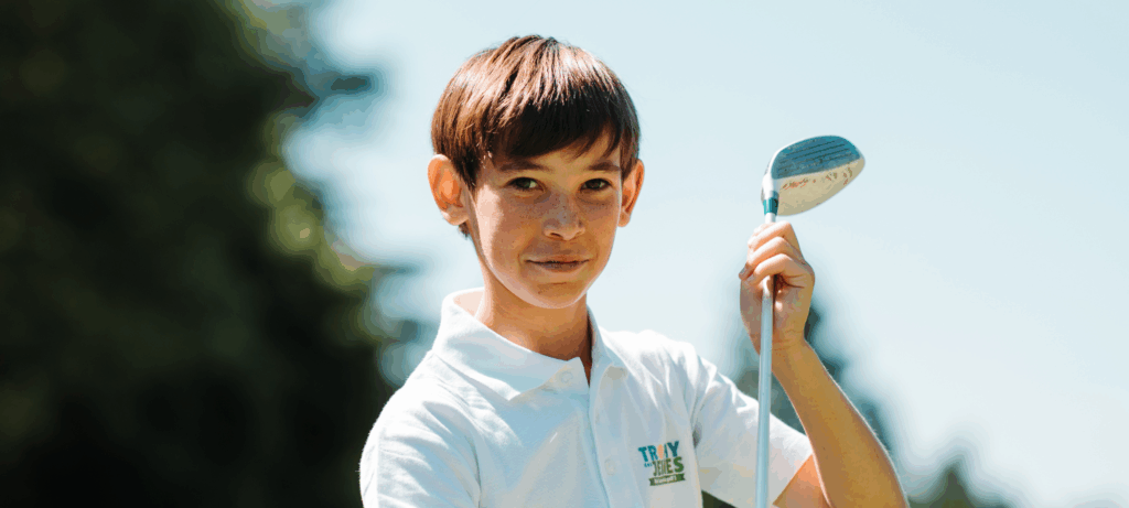 Jeune golfeur souriant avec son premier club de golf junior