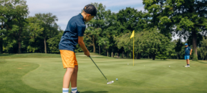 Jeune golfeur de 10 ans concentré sur un putt, illustrant le lien entre golf et concentration scolaire