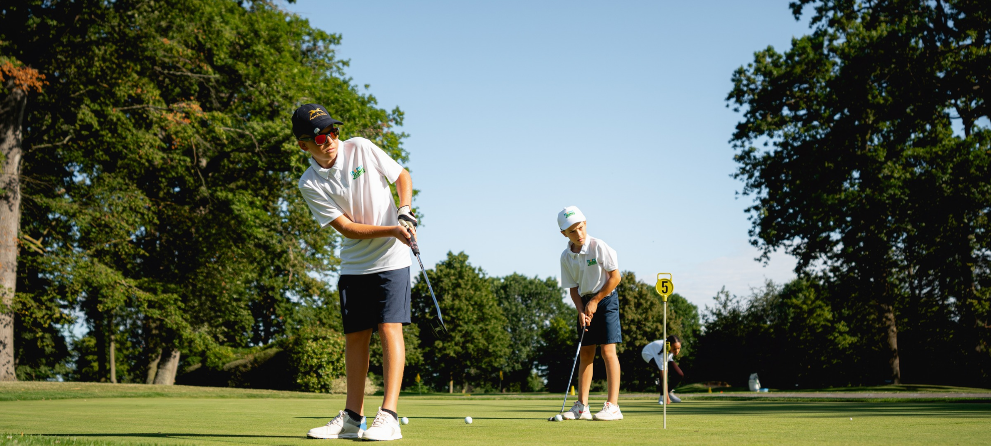 Jeune golfeur souriant s'entraînant au practice après l'école, ambiance détendue.
